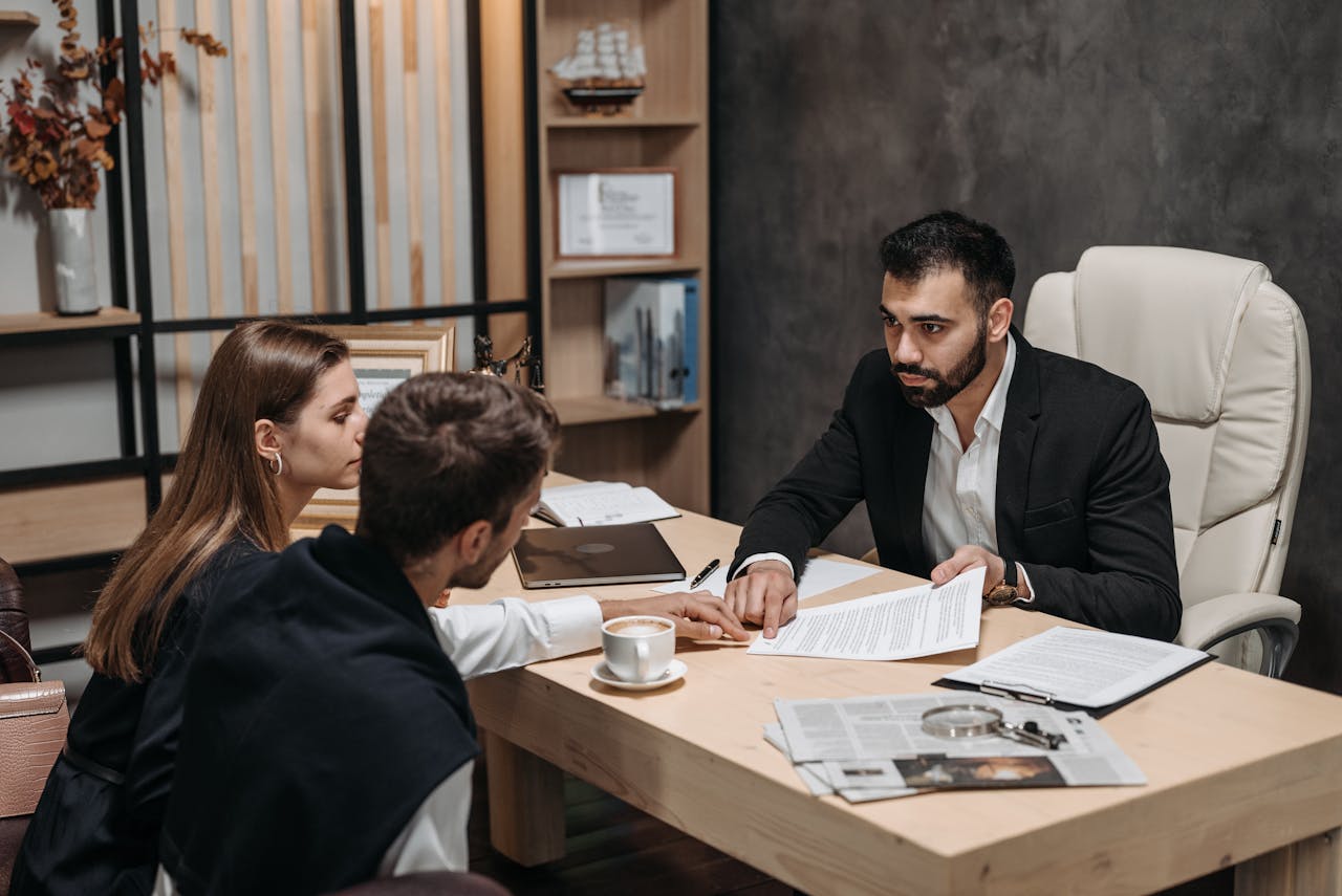 Lawyer discussing legal documents with clients at office desk.